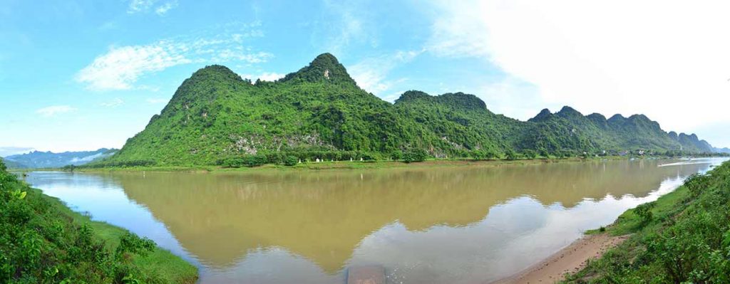 Phong Nha, Vietnam A river with green mountains in the background.