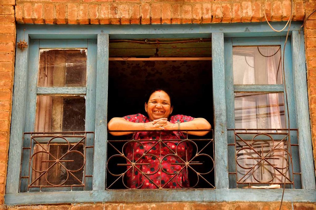 Woman standing by a window, smiling at the camera