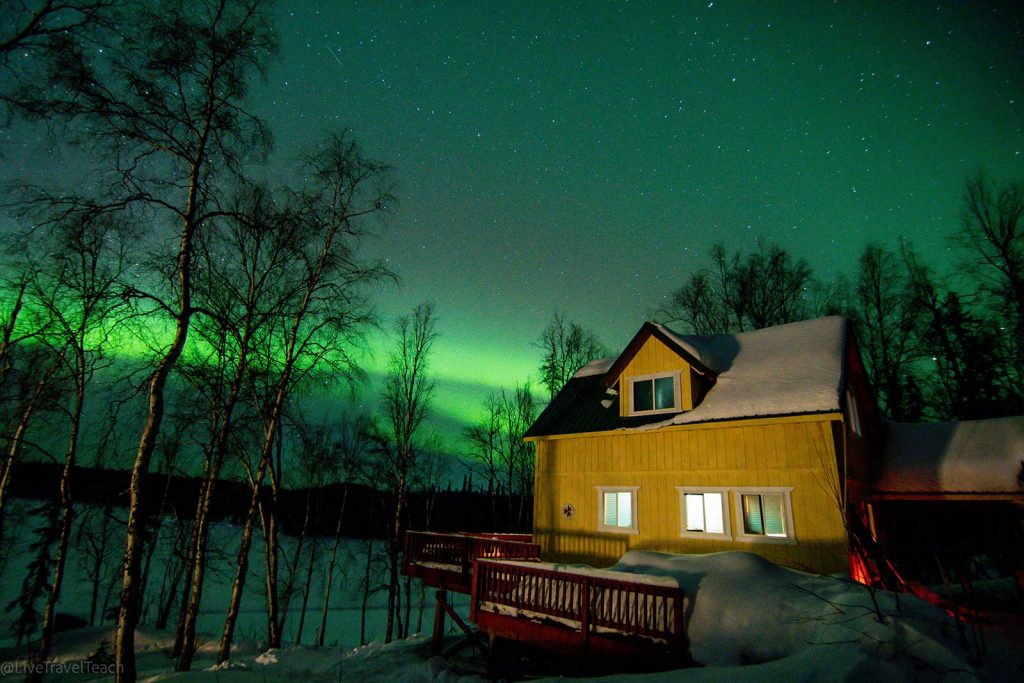 Northern Lights shining brightly over a cabin