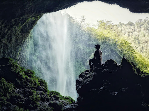 Person sitting on a rock looking at a waterfall in Colorado.