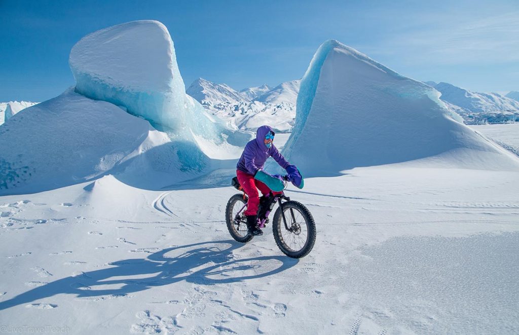 person riding a fat bike through the snowy landscape of the Knik Glacier in Alaska