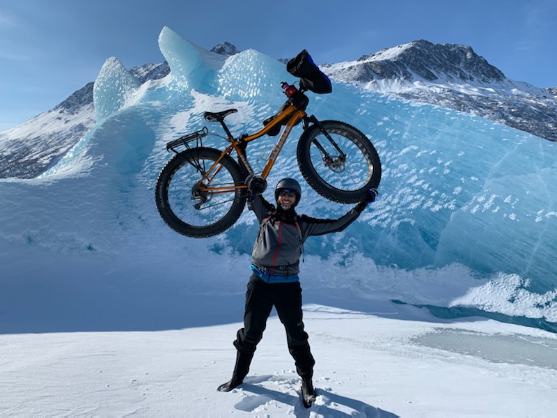 person holding a fat bike against the backdrop of the Knik Glacier