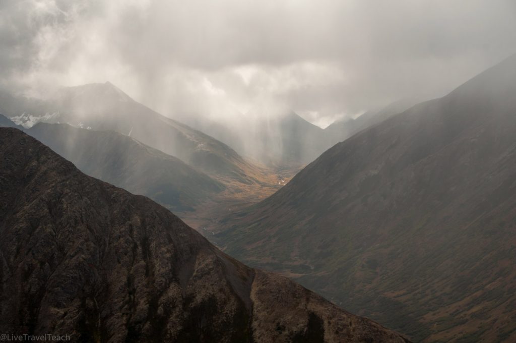 Alaska mountainous landscape with sunbeams breaking through heavy, misty clouds