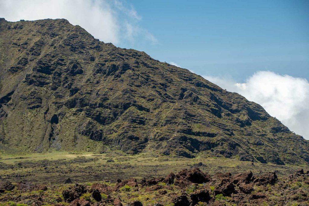 Hiking in Haleakala volcanic terrain with a large, sparse hillside