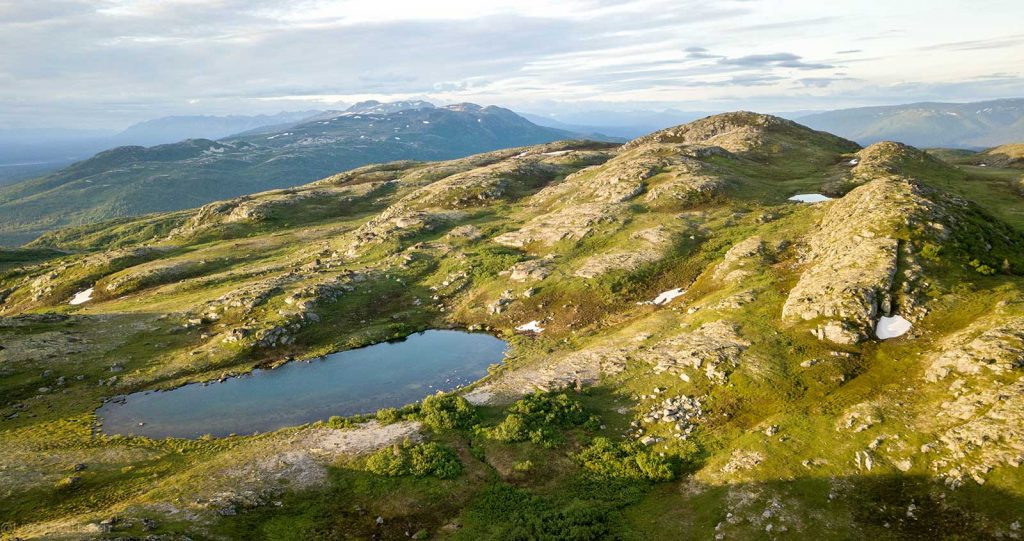 rocky hillsides, patchy snow, and small alpine lakes