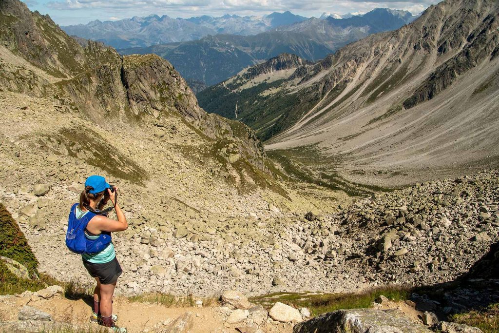Tour du Mont Blanc a hiker taking a photo of the mountain landscape while traversing the Fenêtre d'Arpette pass