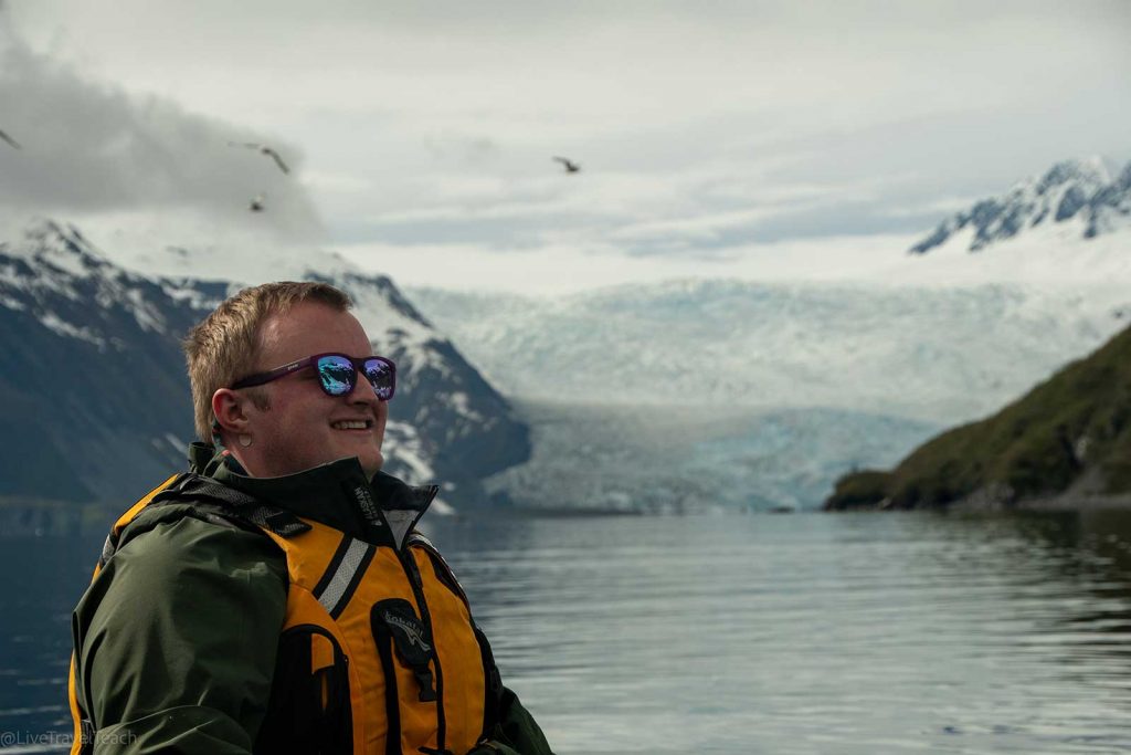 a man smiling with snowy mountains in the background