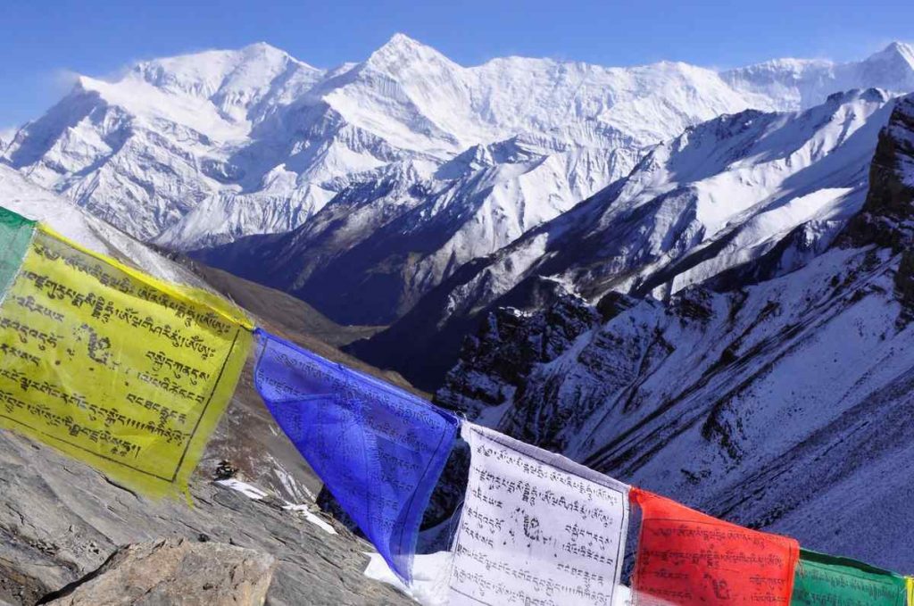 Snow covered mountain in the Annapurna region with colorful prayer flags hanging