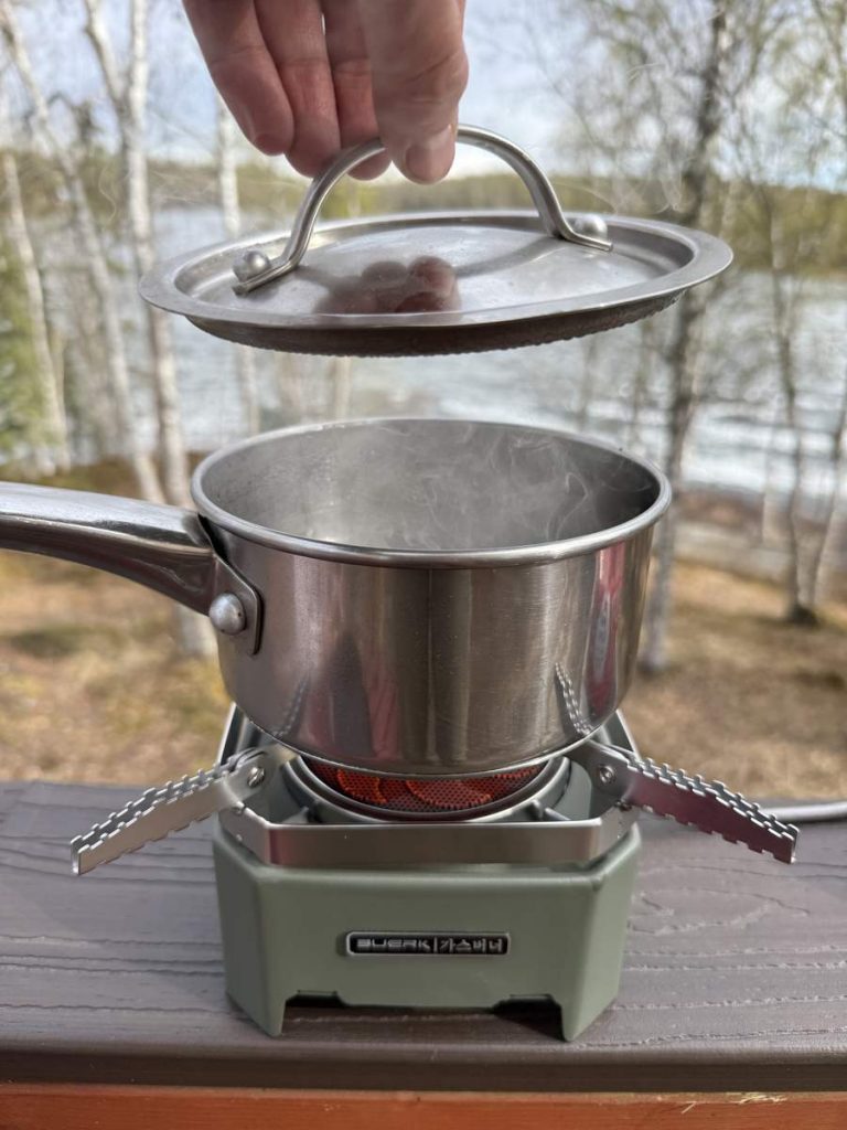 Traverseon lightweight solo camping stove boiling water on a lake cabin deck
